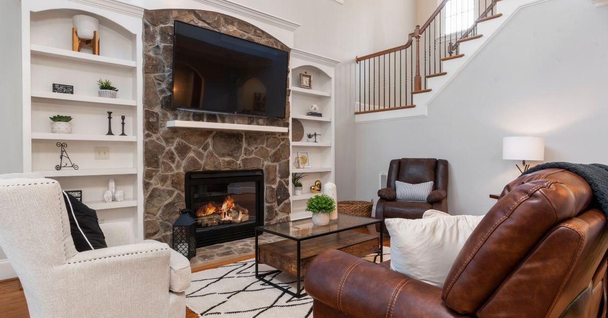 Cozy TV lounge design featuring a stone fireplace, built-in shelves, and comfortable seating in a warm, traditional living room setting.