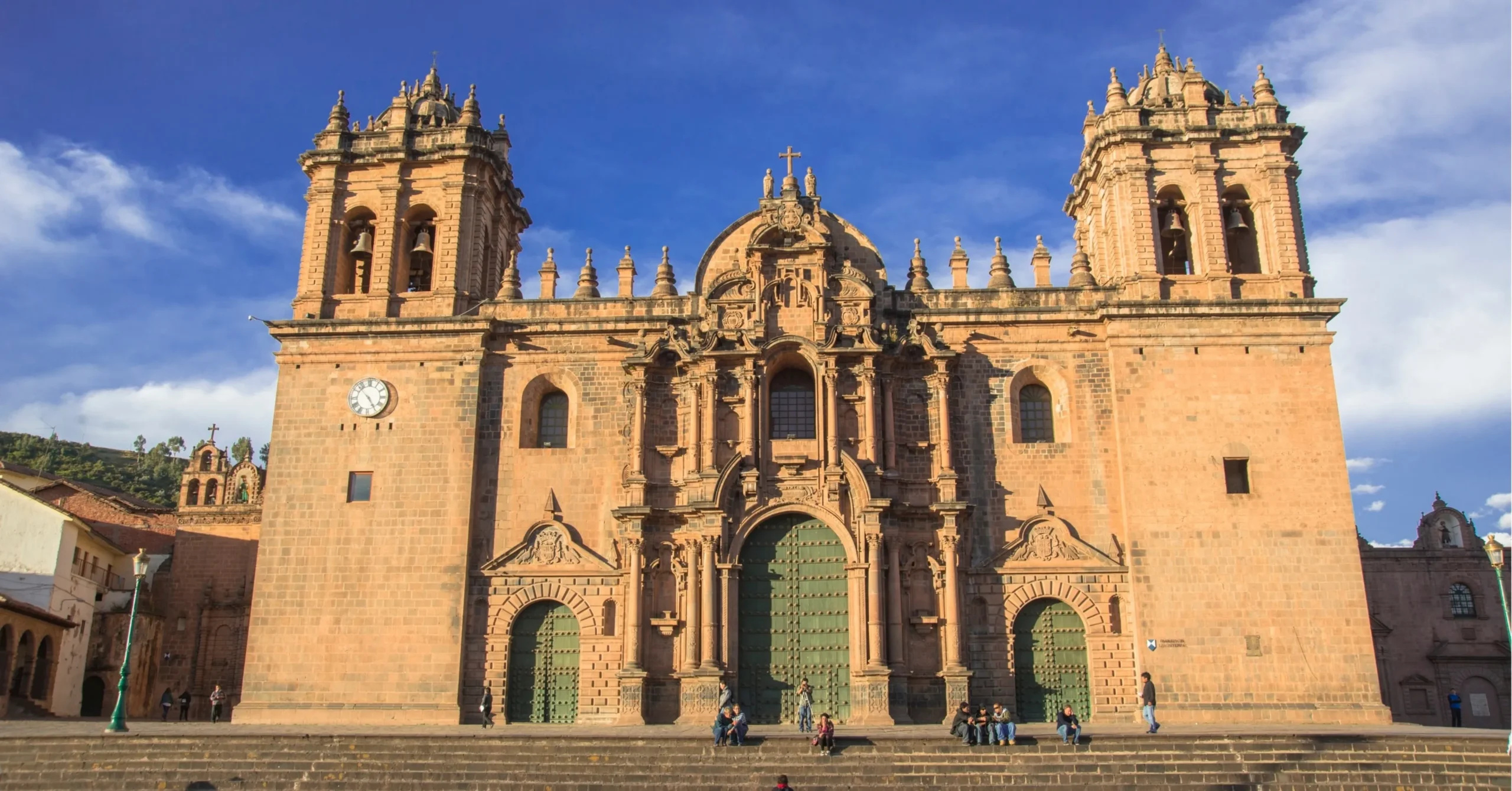 Colonial-era Catholic church with twin bell towers and ornate stone facade under blue sky.