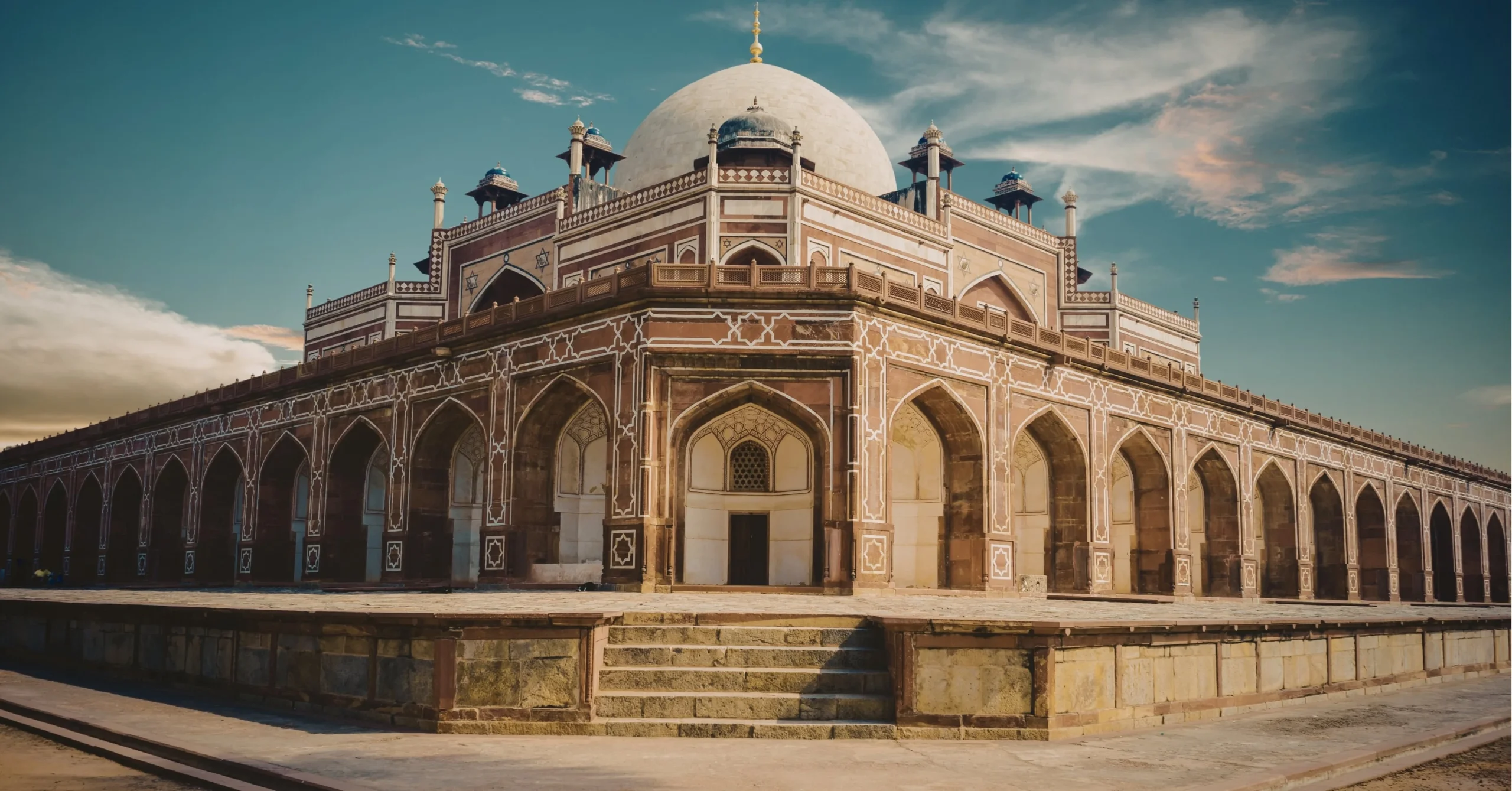 Historic Mughal-era monument with arched architecture and domed structure, likely Humayun's Tomb in Delhi.
